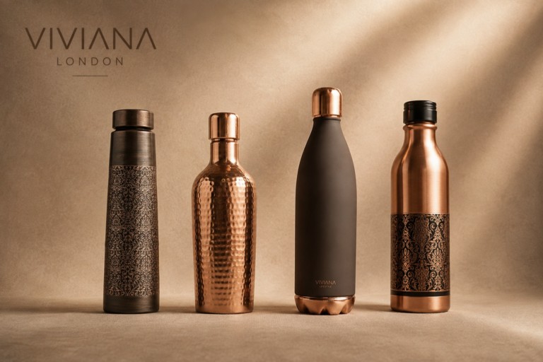 Handcrafted pure copper water bottle set styled on a dark marble desk next to a filled water tumbler