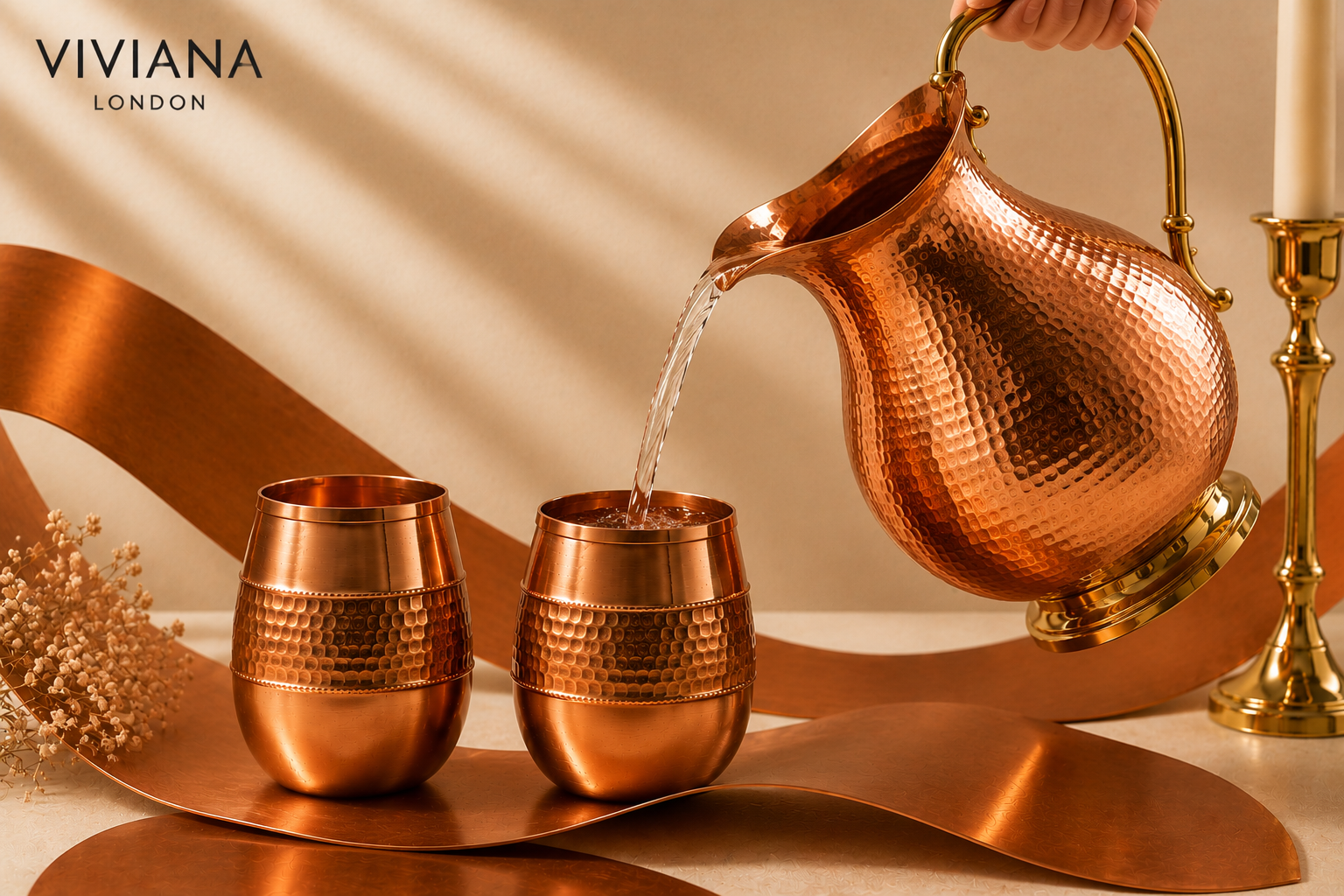 Hand-hammered solid copper water bottle and jug styled on a clean wooden table next to a glass of water